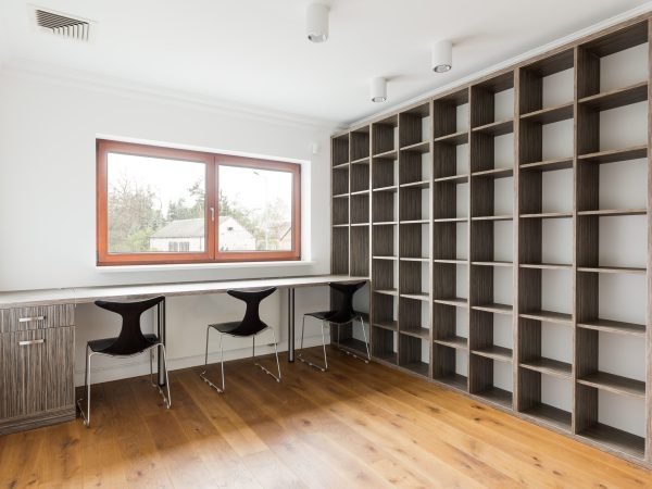 Minimalist empty office with a long desk and a large bookshelf